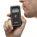 A man blowing into the Andatech AlcoSense Stealth Personal Breathalyser