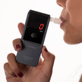 A woman blowing into the Andatech AlcoSense Verity Personal Breathalyser